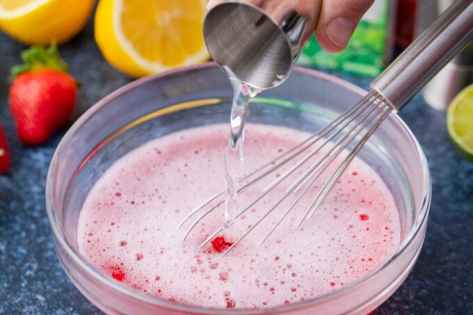 Adding vodka to jello mixture.