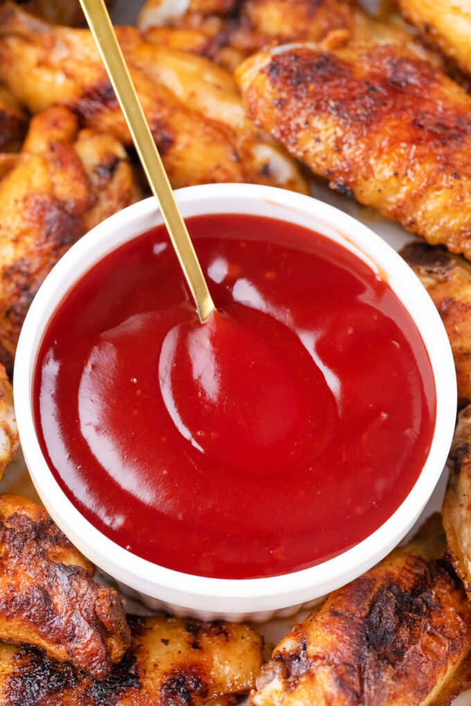 A bowl of sweet and sour sauce served with chicken wings.
