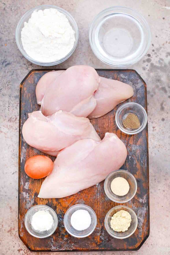 chicken breast spices flour water egg on a cutting board