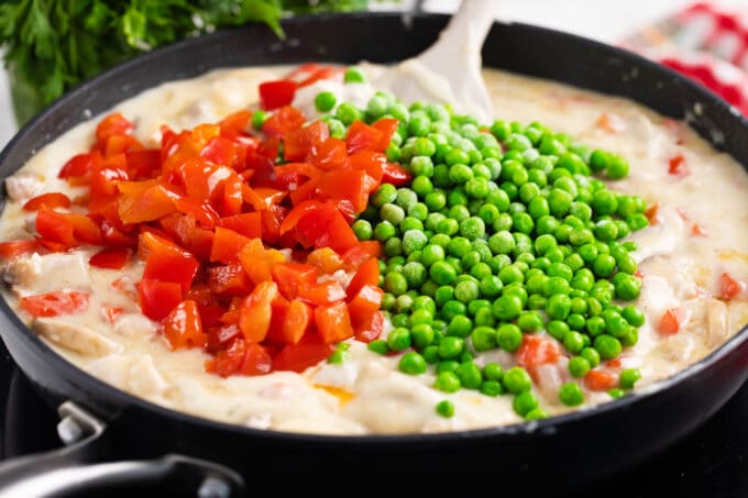 Adding veggies to creamy chicken a la king.