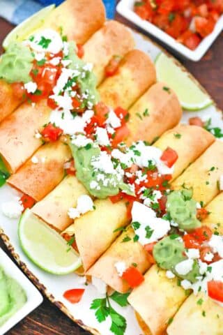 an overhead shot of air fried chicken taquitos topped with guacamole and salsa