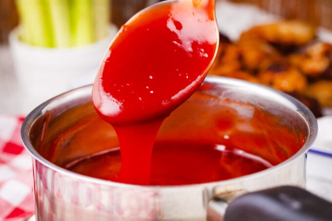 Homemade sweet and sour sauce dripping of a spoon into a pan.