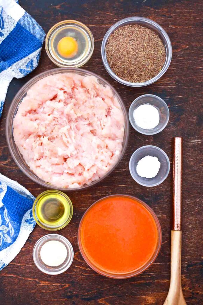 overhead shot of ground chicken spices flaxseed meal and buffalo sauce on a table