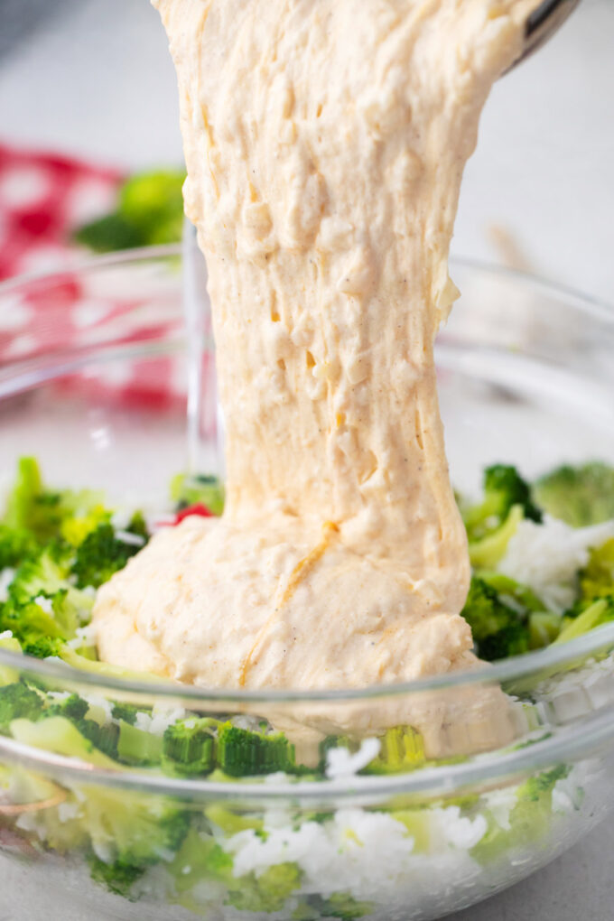Adding cheese sauce to broccoli and rice.