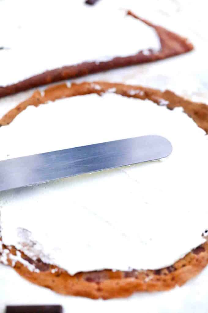 covering a chocolate crepe with whipped cream