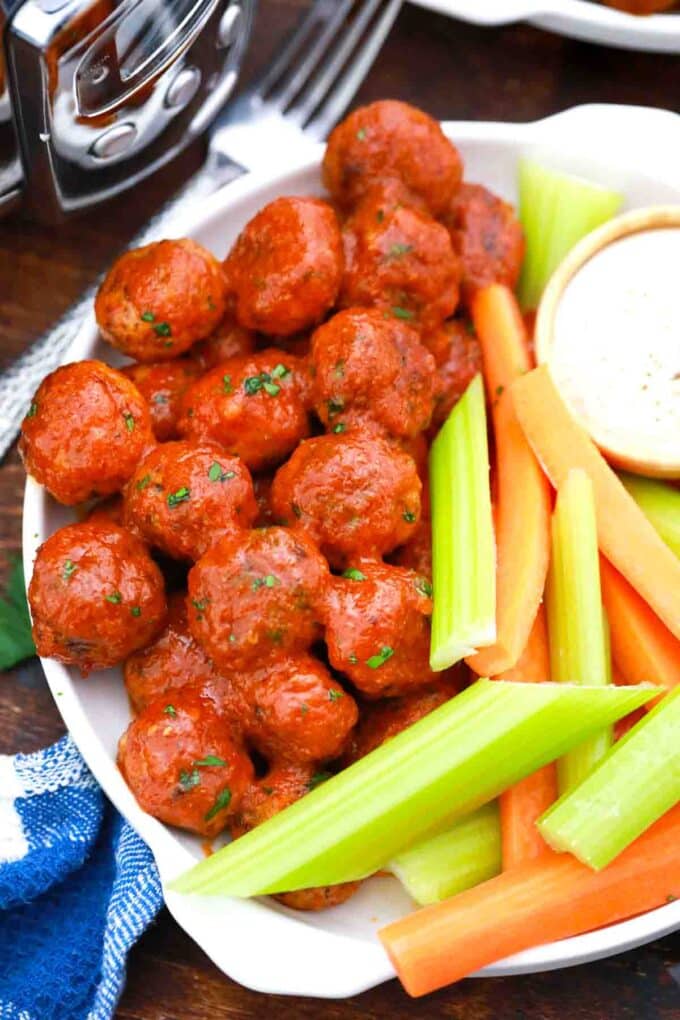 overhead shot of crockpot buffalo chicken meatballs served with veggies and sauce