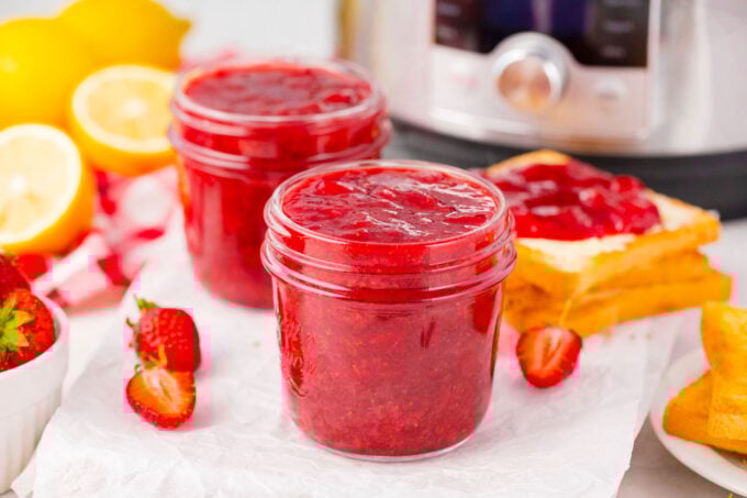 Two jars of instant pot strawberry jam next to a toast and an Instant Pot.