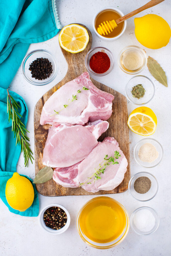 Overhead shot of grilled pork chops brine and rub ingredients arranged on a table.