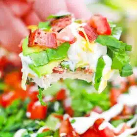 scooping BLT dip with avocado lettuce and tomatoes