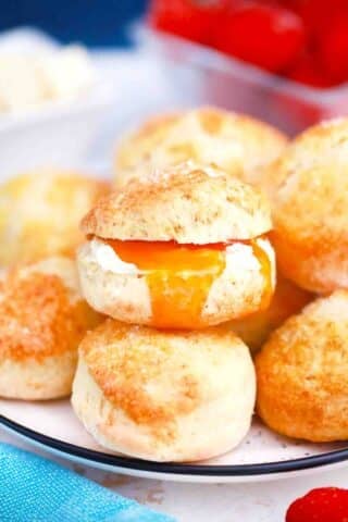 homemade british scones cut in half and stuffed with butter and jam