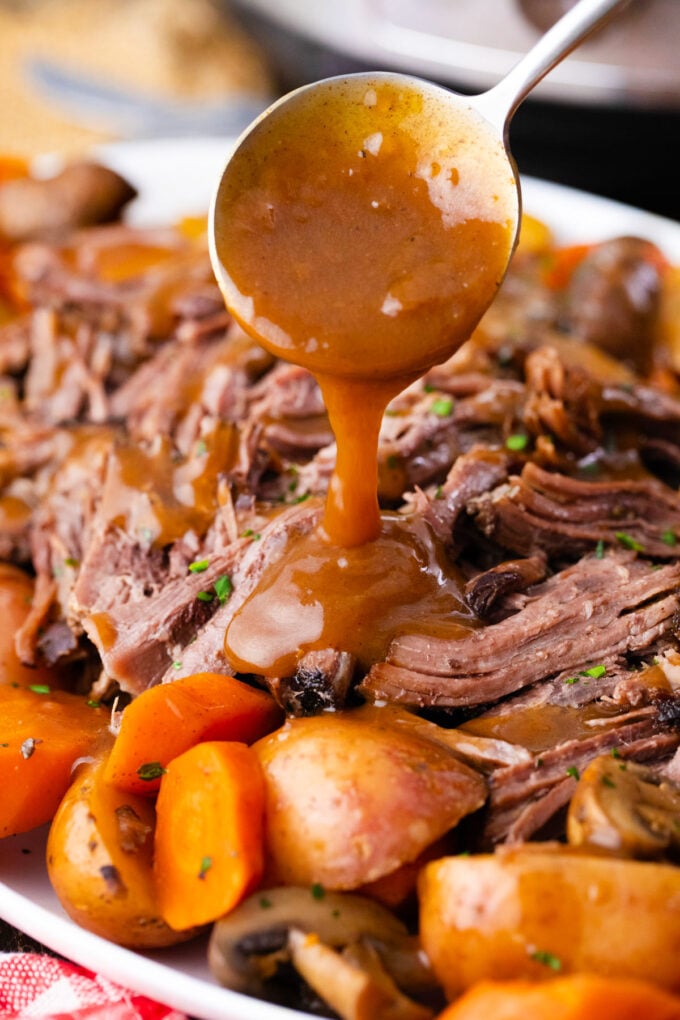 Drizzling gravy over tender, shredded Instant Pot pot roast.