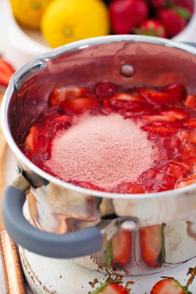 Adding strawberry jello to strawberry pie filling in a saucepan.