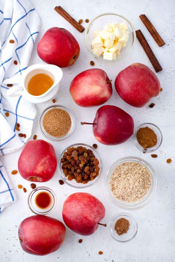 slow cooker baked apples ingredients arranged in bowls, and fresh apples, on a light surface