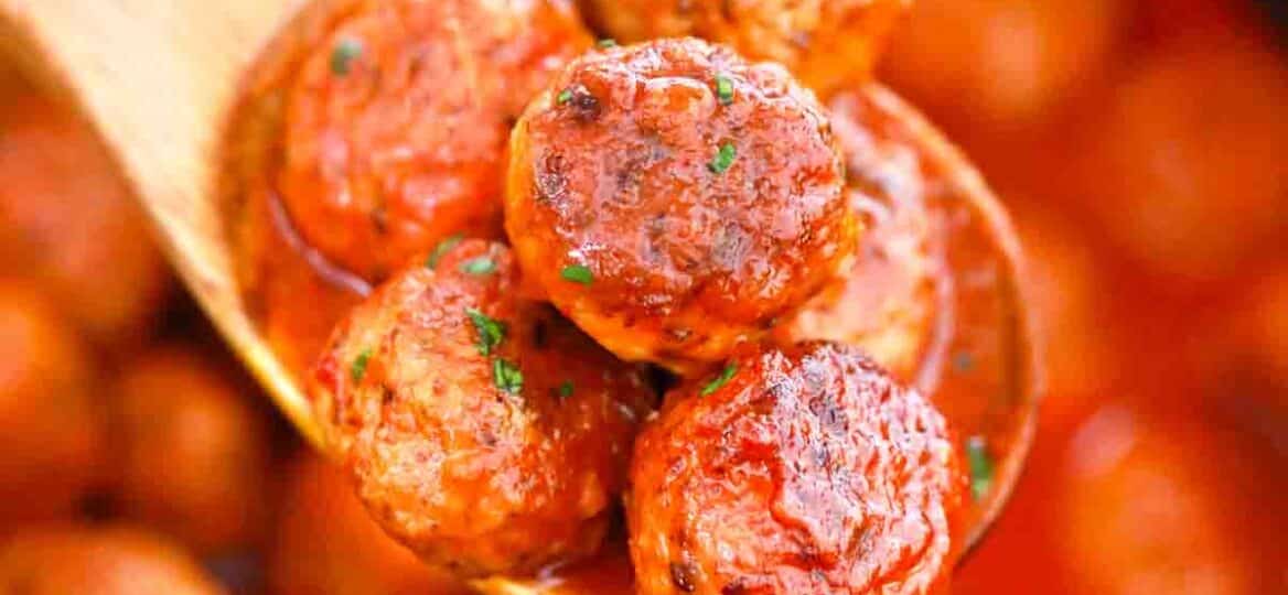 a wooden spoon filled with slow cooker buffalo chicken meatballs