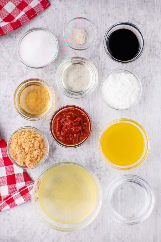Overhead shot of sweet and sour sauce ingredients in bowls on a white surface.