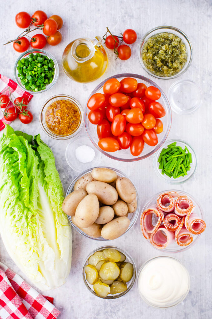 Overhead shot of BLT potato salad ingredients in bowls on a table.
