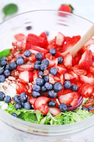 adding fresh berries to a salad