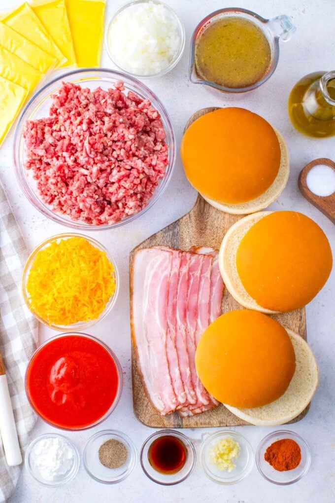 Overhead shot of bacon cheeseburger sloppy joes ingredients arranged on a white surface.
