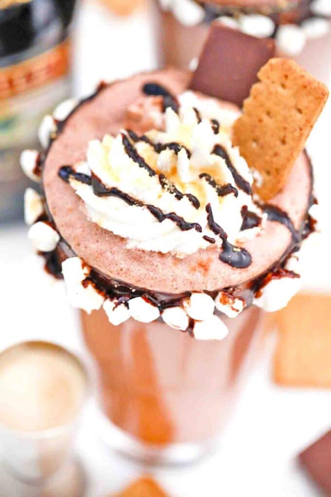 baileys s'mores milkshake with chocolate and marshmallow rim topped with whipped cream and graham crackers