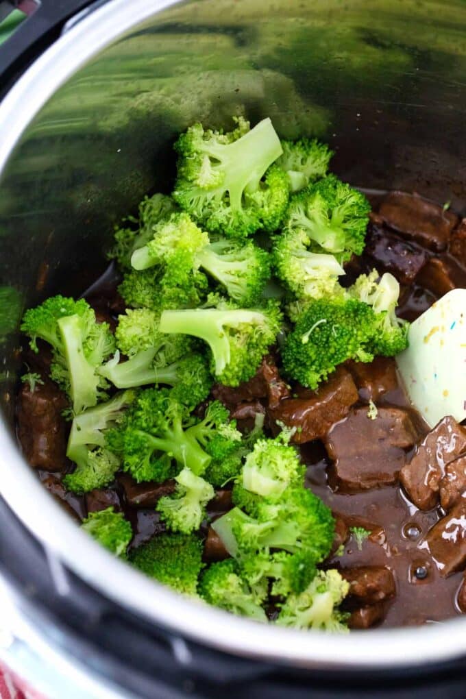 Adding broccoli to pressure cooked beef in the Instant Pot.