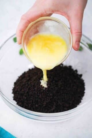 pouring butter on top of Oreo cookie crumbs