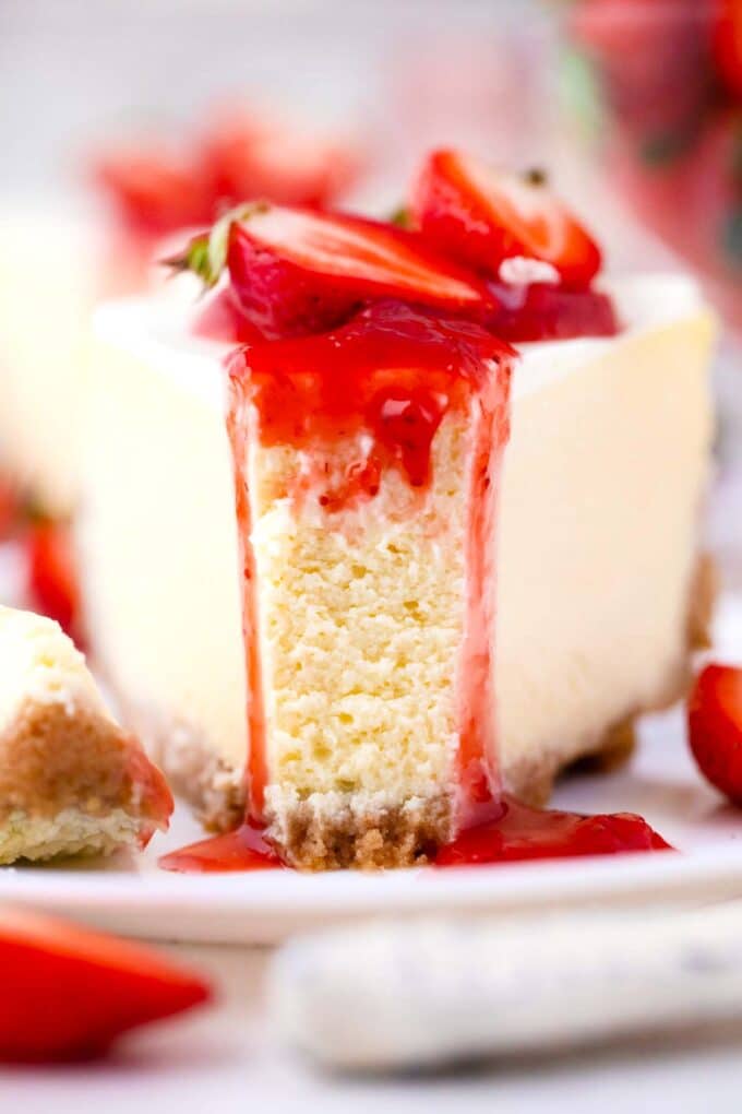 closeup of a slice of cheesecake factory original cheesecake copycat with strawberry sauce dripping and fresh strawberries