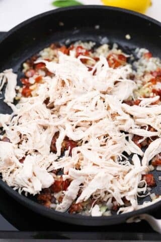 shredded chicken in a pan with bacon onion and garlic