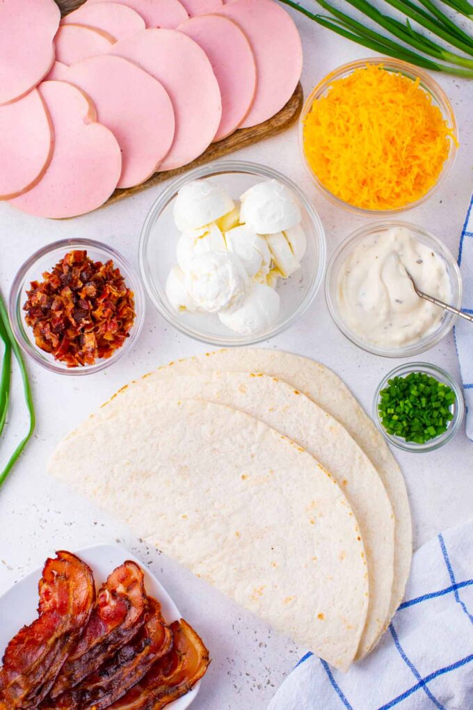 Overhead shot of crack turkey pinwheels ingredients in bowls on a table.