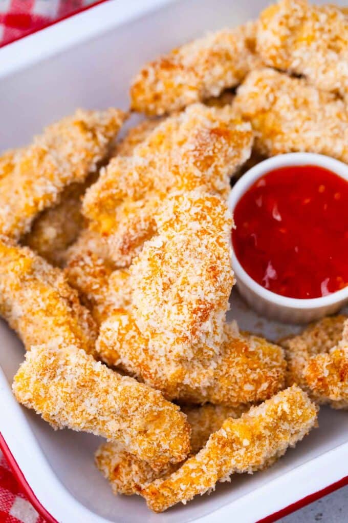 a tray of homemade crispy oven baked chicken tenders served with ketchup