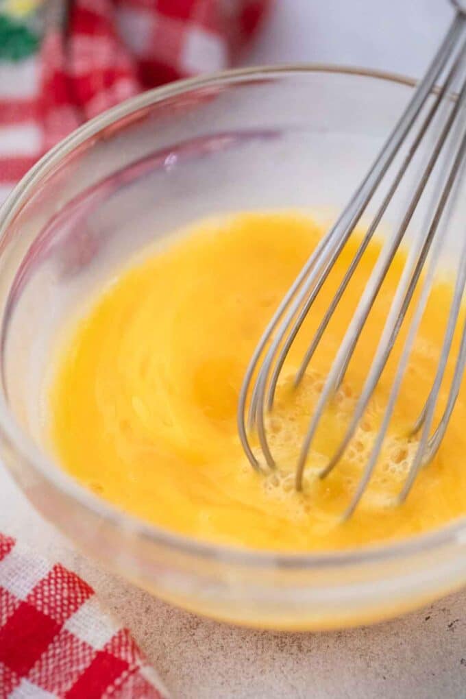 using a whisk to beat eggs in a bowl