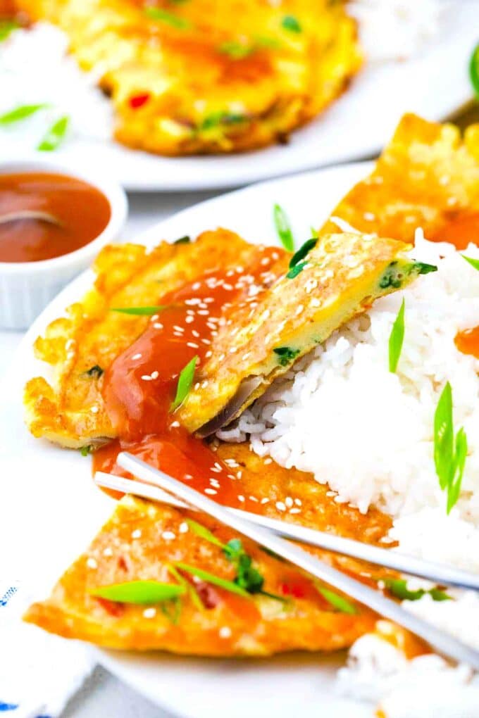 sliced egg foo young topped with sauce, sesame seeds and green onions