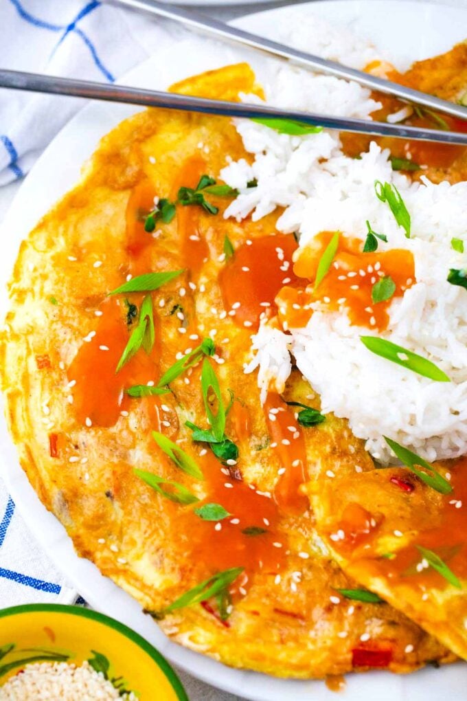 homemade egg foo young with white rice, sauce, and sliced green onions