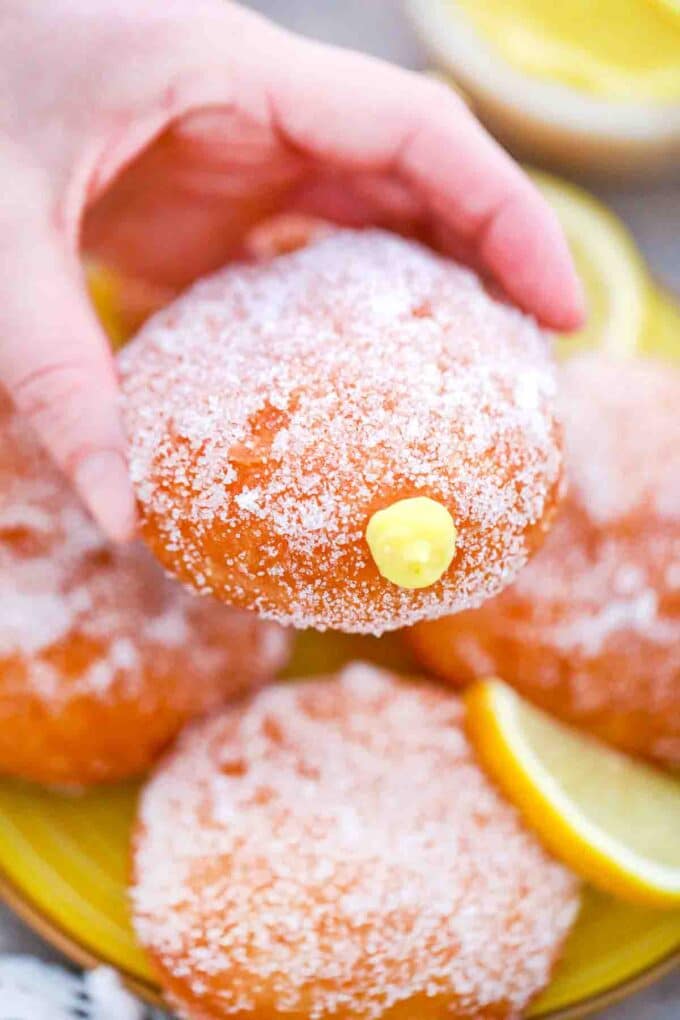 holding a stacked lemon curd filled donut