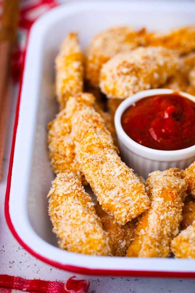 a tray of crispy chicken tenders with ketchup