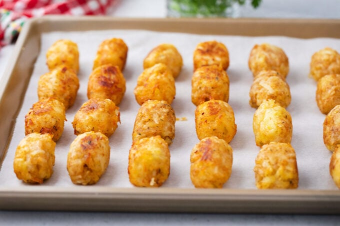 Golden and crispy, homemade tater tots on a baking sheet.