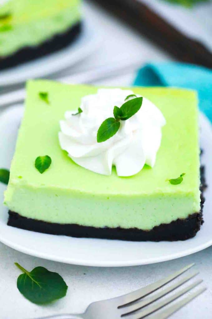 oreo mint cheesecake bars with whipped cream and fresh mint leaves