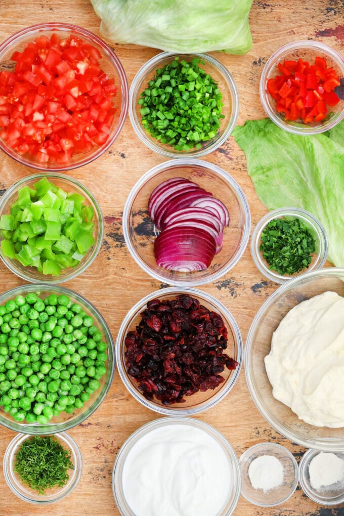 Overhead shot of overnight seven layer salad ingredients in bowls on a wooden surface.