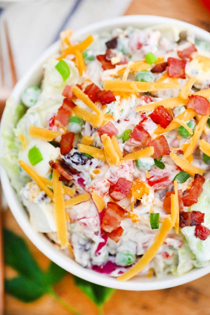 Overhead shot of creamy seven layer salad topped with bacon and cheese.