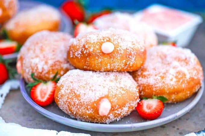 a plate of strawberry custard filled donuts staked