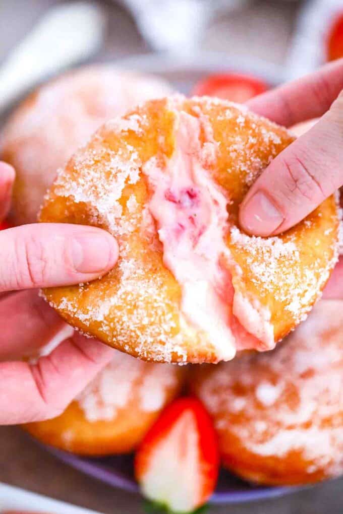 pulling a strawberry custard filled donut in two