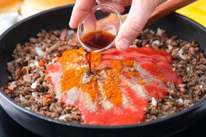 Seasoning beef mixture in a skillet.