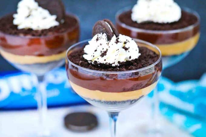 layered 5 minute chocolate oreo pudding in serving glasses topped with whipped cream oreo crumbs and oreo cookie