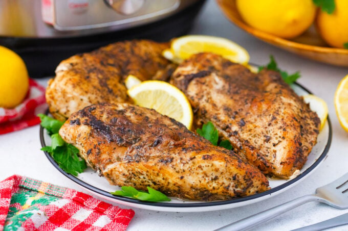 Instant Pot chicken breasts served with lemon wedges.