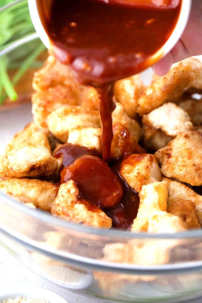 pouring Korean spicy sauce over fried chicken pieces