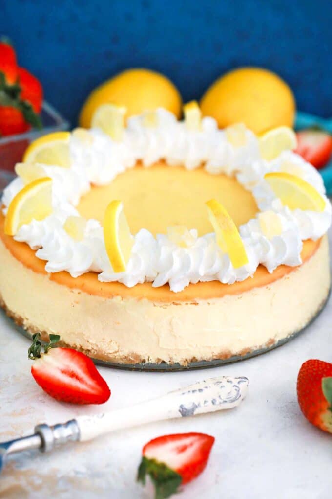 creamy lemon ricotta cheesecake topped with whipped cream and lemon slices