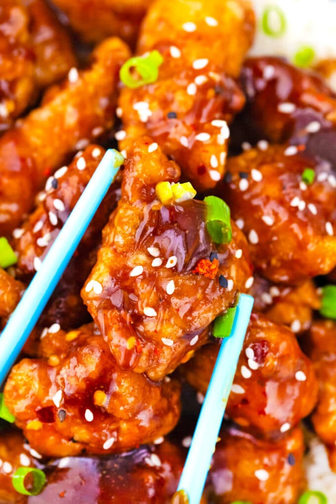 Chopsticks holding crispy and sticky, homemade General Tso's chicken.