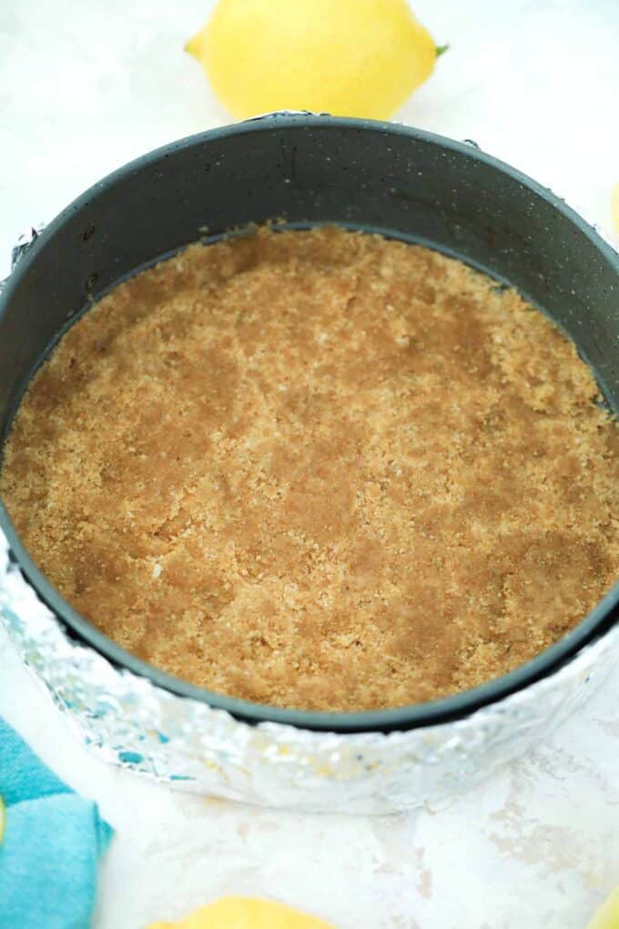 graham cracker crust in a springform pan covered with aluminum foil