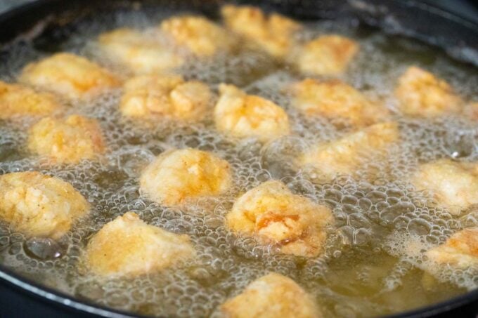 Frying chicken bites in a pan with oil.