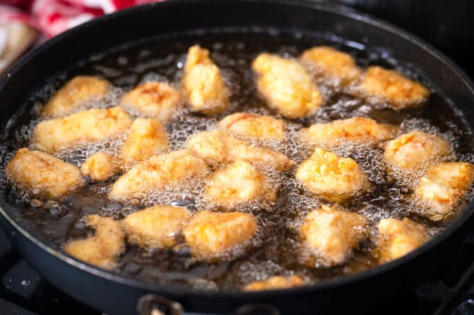 Frying chicken pieces in a cast iron skillet.