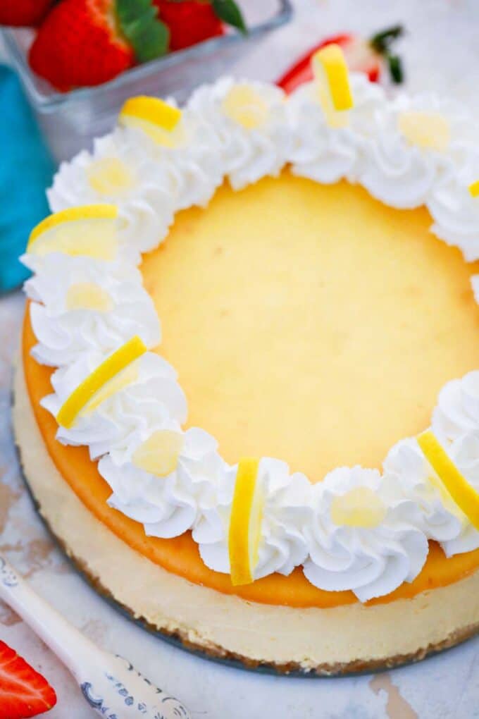 homemade lemon ricotta cheesecake with whipped cream and lemon slices